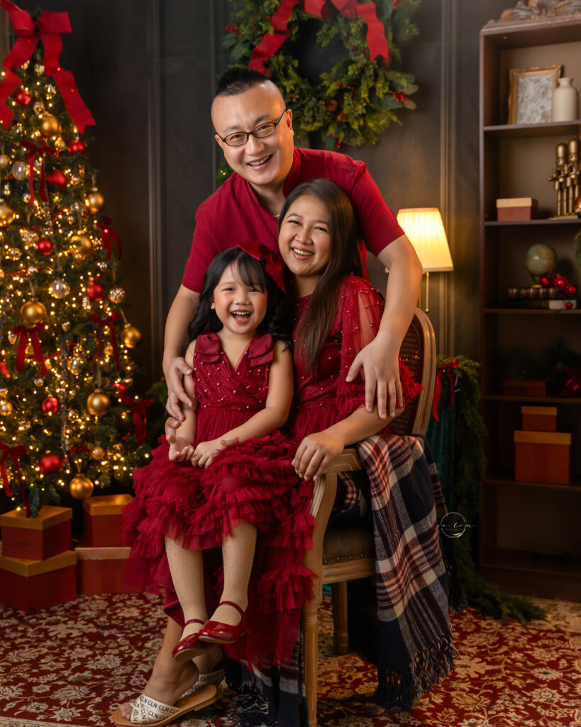 Family - moma, dad and daughter smiling in a Christmas set up.